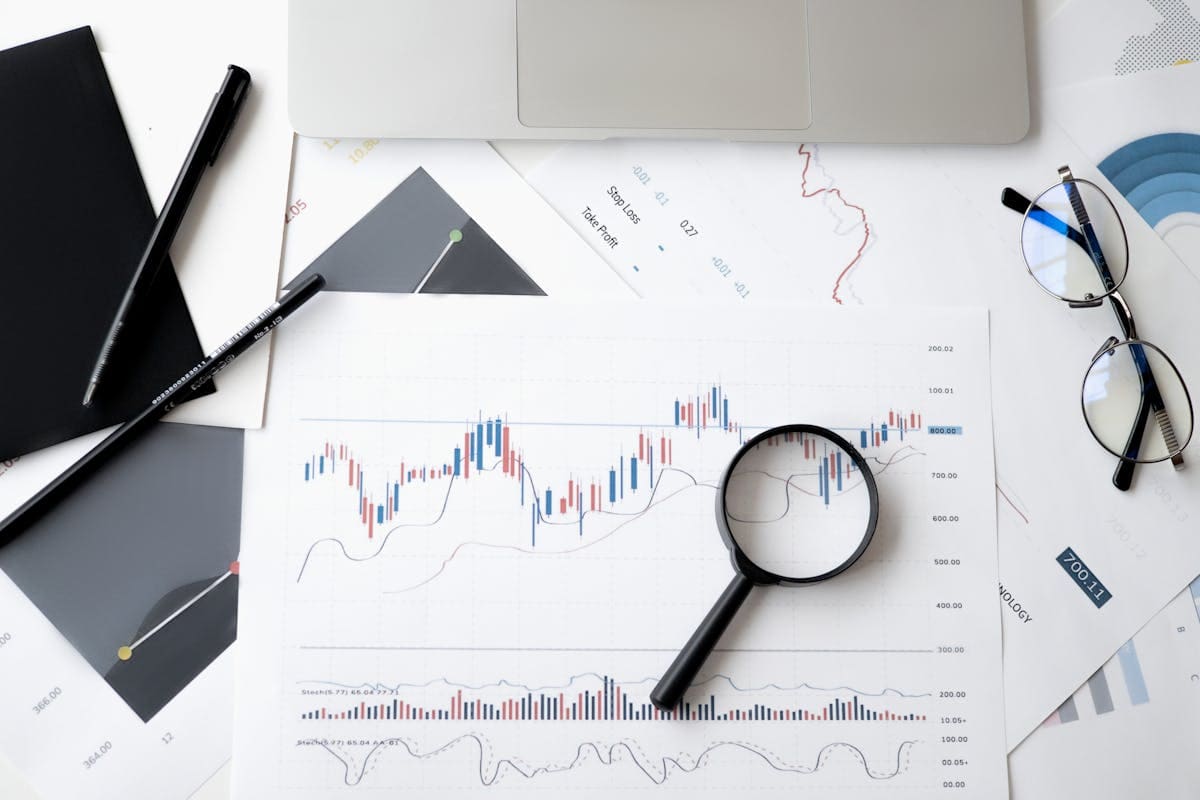 Printed performance charts on a desk with a magnifying glass and reading glasses